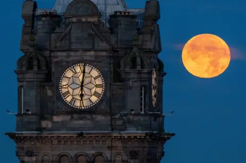 PA A super blue moon, which looks bright orange, next to the Balmoral Clock in Edinburgh last August