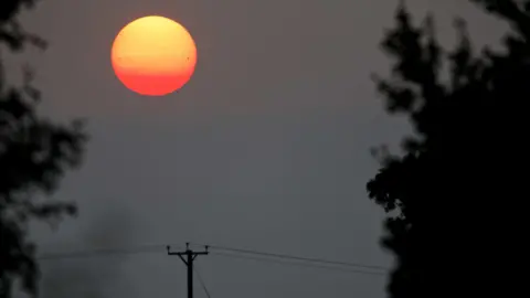 Jamie Cooper A vivid red sunset. A telegraph pole and line can be seen in the foreground.