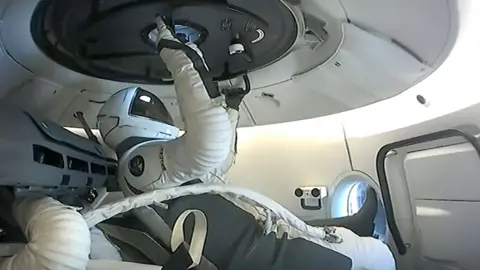 SpaceX A member of Polaris Dawn crew prepares to open the hatch before a space walk