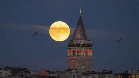 Getty Images Full Moon rises behind the Galata Tower in Istanbul, Turkiye