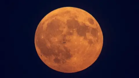 Getty Images A plane flies in front of the Moon in Toronto