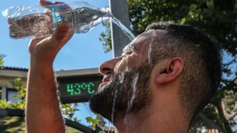 Getty Images Man pours water over his head to cool down