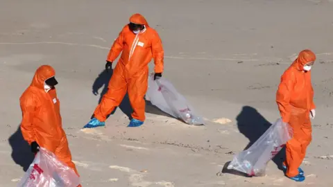 AFP Workers in protective suits conduct a cleanup operation to clear petroleum-based 