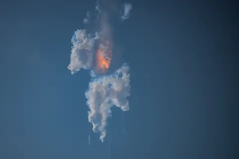 Getty Images Fire and smoke hang in the sky after Starship's explosion.