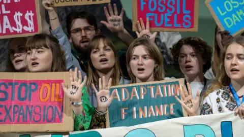 Protesters hold up signs saying 