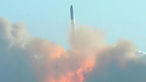 Reuters SpaceX's Starship rocket flies vertically into the air against a clear blue sky, leaving behind clouds of smoke and flames 