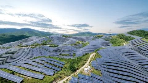 Getty Images Rolling hills in the foreground carpeted by dark blue solar panels