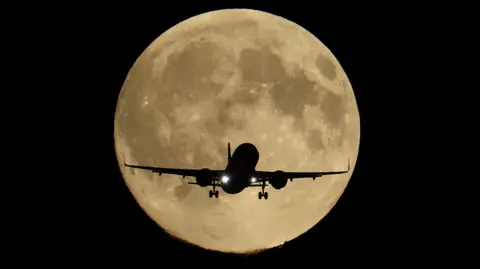 Reuters A flying passenger plan is dwarfed by a sepia-tinged brilliant supermoon